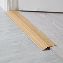 Oak wood effect aluminium threshold ramp fitted across a doorway where laminate meets lower vinyl flooring