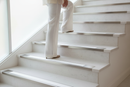 Anti-slip bullnose stair nosing with White insert — installed on UK staircase, semi-rounded profile with person using stairs
