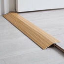 Amber Oak wood effect threshold ramp fitted in a doorway bridging laminate and vinyl flooring