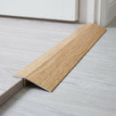 Cognac Oak wood effect threshold ramp fitted in a doorway bridging laminate and vinyl flooring