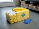 Yellow chemical absorbent pads and coiled yellow socks from a 120 litre spill kit refill pack wrapped in polythene on a workshop floor, with yellow disposal bags, an instruction sheet and blue nitrile gloves