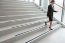 Anti-slip aluminium stair nosing with Grey PVC insert — installed on UK staircase with person using the stairs