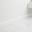 White self-adhesive skirting trim as cove seal at bathroom wall-floor junction