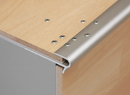 Close-up of push-in aluminium laminate stair nosing gripping laminate tread edge - smooth rounded nose profile