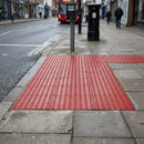 Red blister tactile paving laid at a signal-controlled pedestrian crossing on a British town street