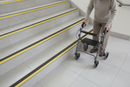 Anti-slip bullnose stair nosing with Yellow insert — installed on UK staircase, semi-rounded profile with person using stairs