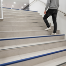 Heavy duty tile-in stair nosing in Cobalt Blue — real-life installation with person using tiled UK staircase