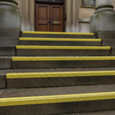 Yellow anti-slip tape on wet outdoor concrete steps — high-visibility grip for external use