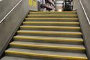 Yellow GRP anti-slip stair nosing installed on industrial concrete steps in UK warehouse