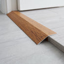 Golden Oak wood effect threshold ramp fitted in a doorway bridging laminate and vinyl flooring