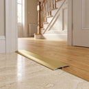 Gold anodised 26mm aluminium T-bar threshold strip fitted between travertine tiles and honey oak flooring in a UK hallway