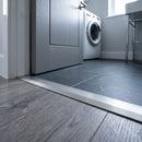 Inox anodised 26mm aluminium T-bar threshold strip fitted between slate grey tiles and grey engineered wood in a UK utility room doorway