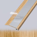 Underside of a wood effect door threshold ramp with the self-adhesive backing film peeled back to expose the tape