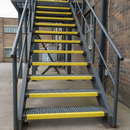 Yellow GRP nosing on external fire escape metal stairs in UK commercial building