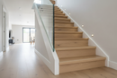 Wood effect uPVC stair nosing on modern UK laminate staircase with glass balustrade - step edge protection