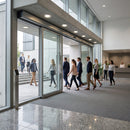 White oak stair nose LED lights illuminating modern office entrance with people walking through glass doors