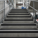 Black GRP heavy duty stair tread covers on industrial factory stairs — full tread coverage permanent anti-slip