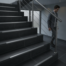 Tile-in aluminium step edging in Inox — installed on tiled UK staircase with person using the stairs