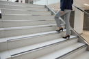 Anti-slip bullnose stair nosing with Grey insert — installed on UK staircase, semi-rounded profile with person using stairs