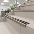 Champagne anodised 36mm slim aluminium stair nosing with twin black rubber inserts on tiled office reception stairs
