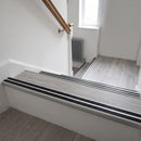 Silver anodised 36mm slim aluminium stair nosing with twin black rubber inserts fitted to grey LVT stair treads in a UK home