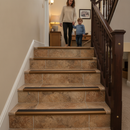 Heavy duty tile-in stair nosing in Brown — real-life installation on tiled UK staircase with person using the stairs