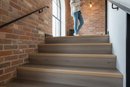 uPVC wood effect stair nosing in Smoked Oak — real-life installation on UK staircase with person using the stairs