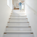 Heavy duty tile-in stair nosing in White installed on tiled UK staircase with person using the stairs - real-life use case