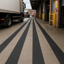 Multiple widths of black anti-slip tape applied in warehouse loading dock floor safety lanes