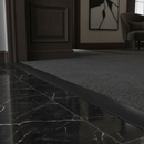 Black PVC floor transition strip in luxury UK interior between marble tile and dark carpet
