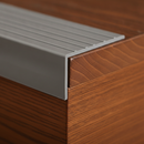 Close-up of grey self-adhesive PVC stair nosing 50×48mm showing anti-slip groove pattern installed on step