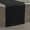 Close-up of silicon carbide grit surface on black anti-slip tape — coarse aggressive grip texture