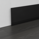 Close-up of black self-adhesive vinyl skirting board trim 100mm installed at wall-floor junction