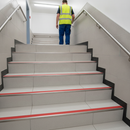 Heavy duty tile-in stair nosing in Red — real-life installation with person using tiled UK staircase