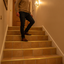 Tile-in aluminium step edging in Gold — installed on tiled UK staircase with person using the stairs