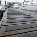 Dark grey 50mm fine grit GRP anti-slip strips screwed across a wet marina pontoon walkway