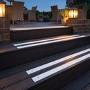 White 50mm fine grit GRP anti-slip strips on dark timber steps of a hotel garden terrace at dusk
