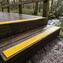 Yellow 50mm fine grit GRP anti-slip strips marking the step edges of a country park footbridge
