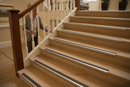 Anti-slip bullnose stair nosing with Beige insert — installed on UK staircase, semi-rounded profile with person using stairs