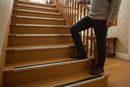 Anti-slip aluminium stair nosing with Brown PVC insert — installed on UK staircase with person using the stairs