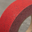 Close-up of red silicon carbide anti-slip tape grit surface — coarse texture for maximum grip