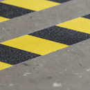 Close-up of black and yellow diagonal chevron anti-slip tape surface showing silicon carbide grit texture