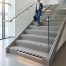Heavy duty tile-in stair nosing in Dolphin Grey — real-life installation with person using tiled UK staircase