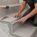 Professional tiler installing tile-in aluminium step edging on ceramic staircase - trade installation photograph