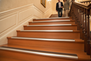 Anti-slip bullnose stair nosing with Brown insert — installed on UK staircase, semi-rounded profile with person using stairs