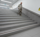 DDA anti-slip aluminium stair nosing 70mm x 56mm installed on wide UK public building staircase - elderly person with walking stick using stairs safely