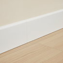 Close-up of white self-adhesive vinyl skirting board trim 100mm installed flush at wall-floor junction