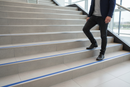 Anti-slip bullnose stair nosing with Blue insert — installed on UK staircase, semi-rounded profile with person using stairs
