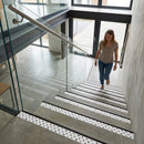 Woman walking down modern stairs with anti-slip stair nosing strips applied to concrete steps
