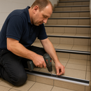 Contractor installing anti-slip aluminium stair nosing on commercial UK building tiled staircase - professional retrofit installation